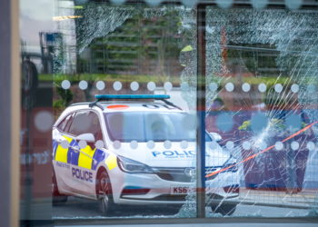 UK riots August 2024, police car in front of a damaged office block in Sunderland
