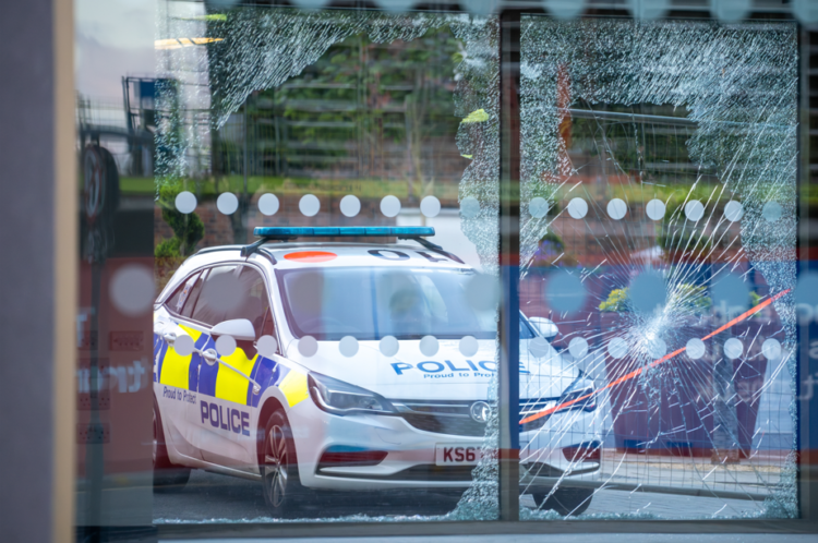UK riots August 2024, police car in front of a damaged office block in Sunderland